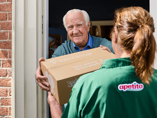 Bezorgster van apetito overhandigt een dinerdoos aan de klant